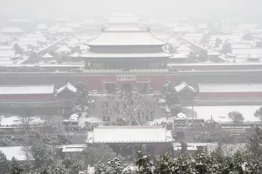 The snow covered Forbidden City is seen from a hilltop pavilion in Beijing, Wednesday, Dec. 13, 2023. Throngs of people in boots and down parkas climbed a hill that overlooks the Forbidden City this week to jostle with others trying to get a shot of the snow-covered roofs of the former imperial palace. (AP Photo/Ng Han Guan)