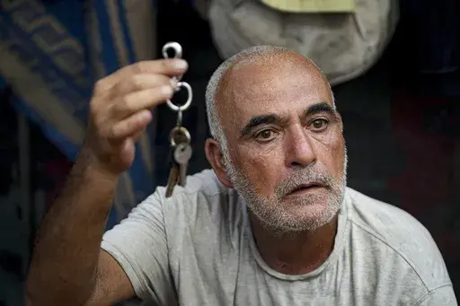 Hassan Nofal, 53, who was displaced by the Israeli bombardment of the Gaza Strip, holds the keys to his home that he was forced to leave with his family at a makeshift tent camp in Khan Younis, southern Gaza Strip, Thursday, July 4, 2024. Over nine months of war between Israel and Hamas, Palestinian families in Gaza have been uprooted repeatedly, driven back and forth across the territory to escape the fighting. Each time has meant a wrenching move to a new location and a series of crowded, temp