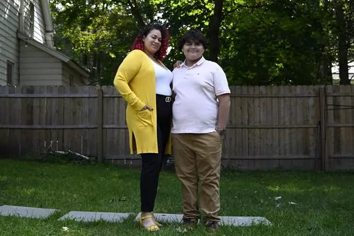 Rousmery Negrón stands with her son at home in Springfield, Mass., on Thursday, Aug. 3, 2023. When in-person school resumed after pandemic closures, Negrón and her son both noticed a change: School seemed less welcoming. Parents were no longer allowed in the building without an appointment, Negrón said. Punishments were more severe. Everyone seemed less tolerant, more angry. Negrón's son even overheard a teacher mocking his learning disabilities, calling him an ugly name. He would end up mis