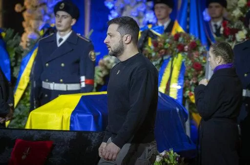 Ukrainian President Volodymyr Zelenskyy pays his respects to victims of a deadly helicopter crash during a farewell ceremony in Kyiv, Ukraine, Saturday, Jan. 21, 2023. Interior Minister Denys Monastyrsky, his Deputy Yevhen Yenin, State Secretary Yurii Lubkovych, national police official and the three crew members were killed in a helicopter crash on Wednesday in Kyiv suburbs of Brovary. (AP Photo/Efrem Lukatsky)