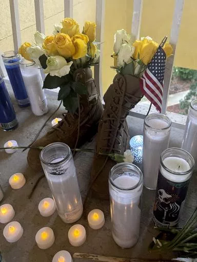 A small shrine is pictured Monday, May 13, 2024, in Fort Walton Beach, Fla. at the door of an apartment where a Florida deputy shot and killed Senior Airman Roger Fortson. The shrine includes a long wooden plank, anchored by two sets of aviator wings and a black marker to leave thoughts, a Stella Artois, and combat boots and an American Flag. As the unit takes a day to grieve and prepare for a funeral Friday, May 17, questions remain about the shooting. (AP Photo)