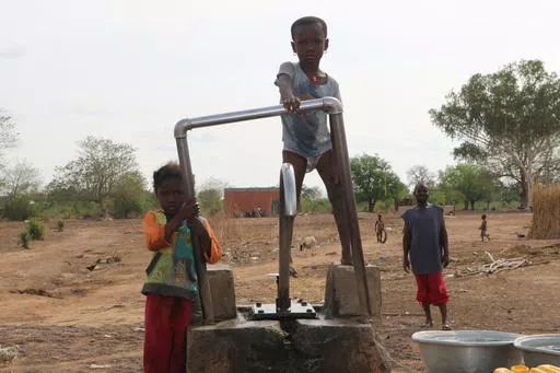 FILE- Children play on a water pump in an internally displaced camp in Gaoa, Burkina Faso, April 22, 2021. More than half of the displaced by growing violence between Islamic extremists and security forces are children, and many are traumatized by their experiences. But mental health services in the West African country are limited, and children are often overlooked for treatment.(AP Photo/Sam Mednick, File)