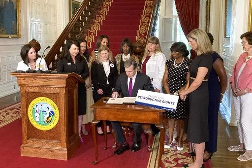North Carolina Democratic Gov. Roy Cooper signs an executive order designed to protect abortion rights in the state at the Executive Mansion in Raleigh, N.C. on Wednesday, July 6, 2022. The order in part prevents the extradition of a woman who receives an abortion in North Carolina but may live in another state where the procedure is barred. (AP Photo/Gary D. Robertson).
