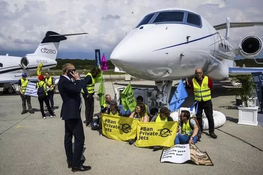 Environmental activists of Stay Grounded and Greenpeace demonstrate while handcuffing themselves to a plane during the European Business Aviation Convention and Exhibition (EBACE), at the Geneve Aeroport in Geneva, Switzerland, May 23, 2023. Climate activists have spraypainted a superyacht, blocked private jets from taking off and plugged holes in golf courses this summer as part of an intensifying campaign against the emissions-spewing lifestyles of the ultrawealthy. (Laurent Gillieron/Keystone