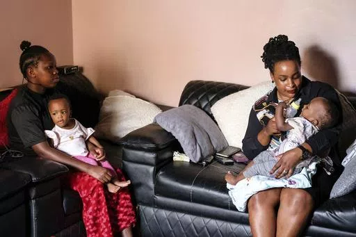 Caroline lkendi, right, feeds her twin son Creflo Curtis with formula milk as nanny, Hadijja, left, carries her other son Roylty Curtis at lkendi's home in Kampala, Uganda, Tuesday, May 21, 2024. ATTA Breastmilk Community was launched in 2021, by a woman who had struggled like Ikendi without getting support. The registered nonprofit, backed by grants from organizations and individuals, is the only group outside a hospital setting in Uganda that conserves breast milk in substantial amounts. (AP P