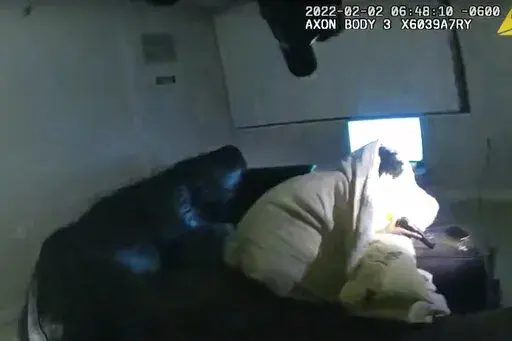 In this image taken from Minneapolis Police Department body camera video and released by the city of Minneapolis, 22-year-old Amir Locke wrapped in a blanket on a couch holding a gun moments before he was fatally shot by Minneapolis police as they were executing a search warrant in a homicide investigation on Wednesday, Feb. 2, 2022, in Minneapolis. Authorities have not said if Locke was connected to the homicide investigation or named in the warrant. (Minneapolis Police Department via AP)
