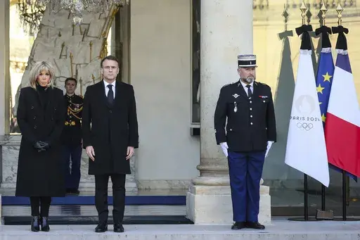 French President Emmanuel Macron and his wife Brigitte Macron stand for a minute of silence Monday, Dec. 23, 2024 at the Elysee Palace, in Paris, after Macron declared a day of national mourning for the lives lost when Cyclone Chido ripped through the Indian Ocean territory of Mayotte. (AP Photo/Thomas Padilla, Pool)