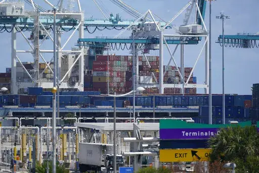 In this April 9, 2021 photo, cargo containers are shown stacked near cranes at PortMiami in Miami. The U.S. trade deficit narrowed to $67.1 billion in October, after hitting a record high the previous month, as a big rebound in exports helped to offset a much smaller rise in imports. The October deficit was 17.6% below the September record of $81.4 billion, the Commerce Department reported Tuesday, Dec. 7, 2021. (AP Photo/Wilfredo Lee, file)