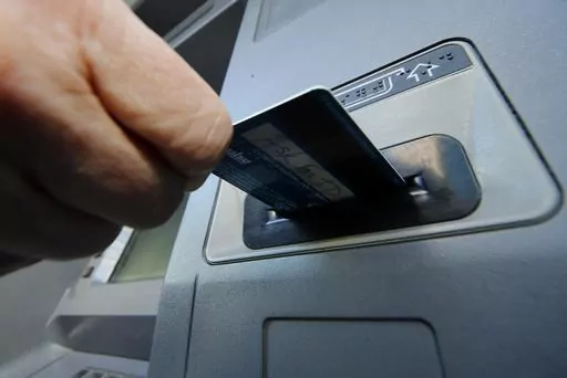 In this Saturday, Jan. 5, 2013 file photo, a person inserts a debit card into an ATM in Pittsburgh. Your college bank account should have the right set of features for you and minimal fees. But banks that partner with universities can offer costly accounts, so be on the lookout for those. Consider what type of banking institution you prefer, whether that’s a big national bank, credit union or other types. (AP Photo/Gene J. Puskar, File)
