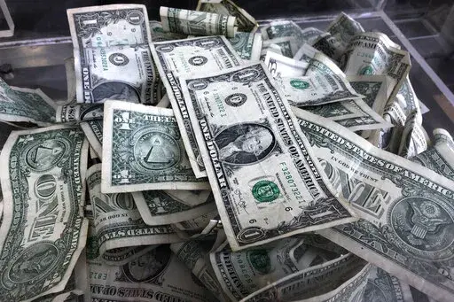 In this Wednesday, April 3, 2019, file photo, a tip box is filled with dollar bills, in New York.  Whether you’re still trying to kick holiday debt to the curb or save money toward a goal, the internet is filled with a variety of challenges on social media that can inspire taking control of your finances. From stashing away spare change to saving according to the weather in your city, you can get creative and competitive about saving money. (AP Photo/Mark Lennihan, File)