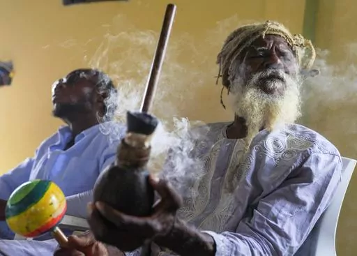 Ras Jah, a member of the Ras Freeman Foundation for the Unification of Rastafari, prepares to pass a chalice pipe with marijuana to the left during service in the tabernacle on Sunday, May 14, 2023, on the Ras Freeman Foundation for the Unification of Rastafari property in Liberta, Antigua. The Rastafari faith is rooted in 1930s Jamaica, growing as a response by Black people to white colonial oppression. The beliefs are a melding of Old Testament teachings and a desire to return to Africa. (AP P