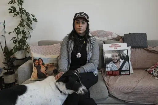 Released hostage Ilana Gritzewsky poses for a portrait in her apartment in Kiryat Gat, Israel, on Sunday, Dec. 15, 2024, near photos of her boyfriend, Matan Zangauker, who is being held hostage by Hamas in the Gaza Strip. (AP Photo/Tsafrir Abayov)