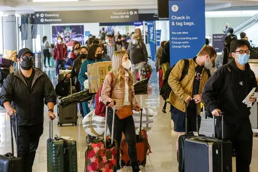 Holiday travelers wearing face masks line to check in at the Los Angeles International Airport in Los Angeles, Wednesday, Dec. 22, 2021. (AP Photo/Ringo H.W. Chiu)