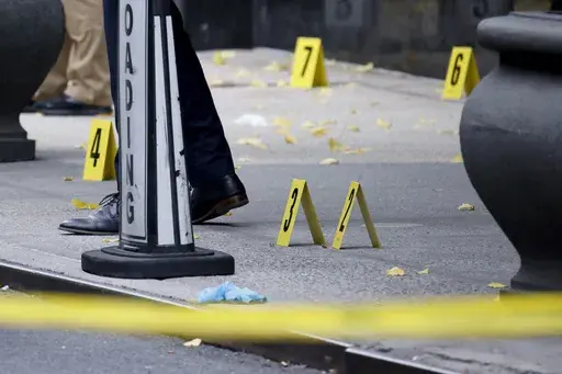 Members of the New York police crime scene unit investigate bullets lying on the sidewalk at the scene outside the Hilton Hotel in midtown Manhattan where Brian Thompson, the CEO of UnitedHealthcare, was fatally shot, Wednesday, Dec. 4, 2024, in New York. (AP Photo/Stefan Jeremiah)