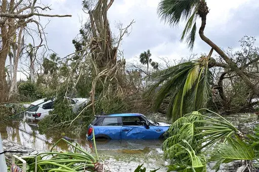 In this undated image from video, damaged vehicles and debris are seen on Sanibel Island, Fla. Chuck Larsen's home was slammed by Hurricane Ian and he spent a harrowing few days on the isolated island before being evacuated over the weekend. (Chuck Larsen/SantivaChronicle.com via AP)