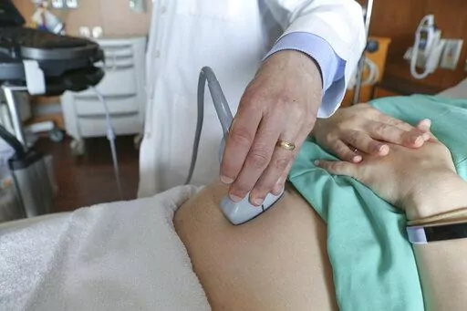 In this Aug. 7, 2018 photo, a doctor performs an ultrasound scan on a pregnant woman at a hospital in Chicago. The arrival of a new baby is all-consuming. You barely know what day it is, and mustering the energy and attention span for managing your financial household can be a tall order. Do your future, sleep-deprived self a favor and start preparing your finances early into your pregnancy. (AP Photo/Teresa Crawford, File)