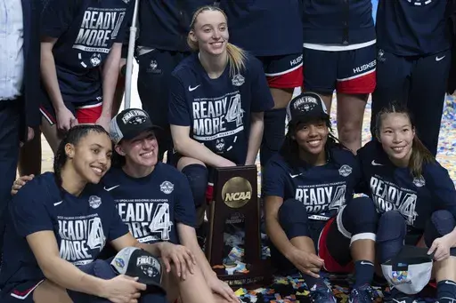 UConn players from left, Azzi Fudd, Ashlynn Shade, Paige Bueckers, KK Arnold and Kaitlyn Chen pose with the trophy after a game against Southern California in the Elite Eight of the NCAA college basketball tournament Monday, March 31, 2025, in Spokane, Wash. (AP Photo/Jenny Kane)