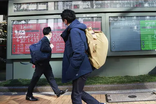 People walk by an electronic stock board of a securities firm in Tokyo, Monday, Dec. 13, 2021. (AP Photo/Koji Sasahara)