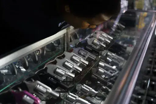 Sales associate Elsworth Andrews arranges guns on display at Burbank Ammo & Guns in Burbank, Calif., Thursday, June 23, 2022. The Supreme Court has ruled that Americans have a right to carry firearms in public for self-defense, a major expansion of gun rights. The court struck down a New York gun law in a ruling expected to directly impact half a dozen other populous states. (AP Photo/Jae C. Hong)