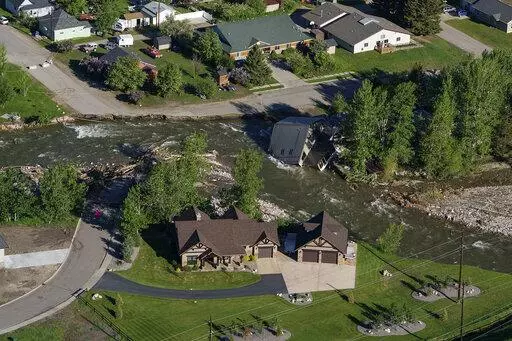 A house sits in Rock Creek after floodwaters washed away a road and a bridge in Red Lodge, Mont., in Red Lodge, Mont., June 16, 2022. (AP Photo/David Goldman, File)
