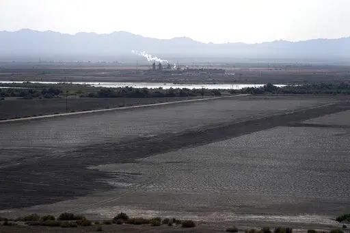 A dried up portion of the Salton Sea stretches out with a geothermal power plant in the distance in Niland, Calif., Thursday, July 15, 2021. Demand for electric vehicles has shifted investments into high gear to extract lithium from geothermal wastewater around the rapidly shrinking body of water. The ultralight metal is critical to rechargeable batteries. (AP Photo/Marcio Jose Sanchez, File)