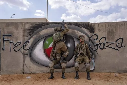 Israeli soldiers climb on a wall as they conduct a mock assault during an urban warfare exercise at an army training facility, in Zeelim army base, southern Israel, Jan. 24, 2022. Officially, the site is known as the Urban Warfare Training Center. But to soldiers, it is known as Mini Gaza, simulating a Palestinian urban area with 500 buildings and narrow alleyways adorned with murals and posters honoring slain fighters. The training center can accommodate exercises for an entire brigade of 2,000