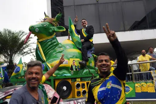 An impersonator of Brazilian President Jair Bolsonaro rides a cow statue during Bolsonaro's campaign event for reelection in Duque de Caxias, Rio de Janeiro state, Brazil, Friday, Oct. 14, 2022. The presidential run-off election is set for Oct. 30. (AP Photo/Silvia Izquierdo)
