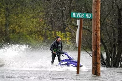 A man operates a personal watercraft along a road flooded by water from the Skagit River, Monday, Nov. 15, 2021, in Sedro-Woolley, Wash. (AP Photo/Elaine Thompson)