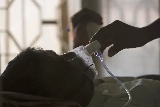 A relative adjusts the oxygen mask of a tuberculosis patient at a TB hospital on World Tuberculosis Day in Hyderabad, India, March 24, 2018. The number of people infected with tuberculosis, including the kind resistant to drugs, rose globally for the first time in years, according to a report issued Thursday, Oct. 27, 2022 by the World Health Organization. (AP Photo/Mahesh Kumar A., File)