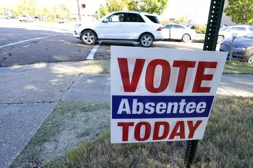 A sign encouraging voters to vote absentee in light of COVID-19 precautions rests on the grounds of the Hinds County Courthouse in Jackson, Miss., Tuesday, Oct. 6, 2020. A federal judge issued an order Tuesday, July 25, 2023, to block a new Mississippi law that would restrict who could help people with absentee voting.(AP Photo/Rogelio V. Solis)