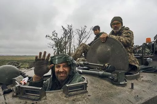 A Ukrainian soldier smiles from a military vehicle on the road in the freed territory in the Kharkiv region, Ukraine, Monday, Sept. 12, 2022. Ukrainian troops retook a wide swath of territory from Russia on Monday, pushing all the way back to the northeastern border in some places, and claimed to have captured many Russian soldiers as part of a lightning advance that forced Moscow to make a hasty retreat. (AP Photo/Kostiantyn Liberov)