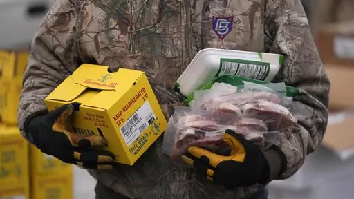 A Utah Food Bank volunteer carries groceries for the needy at a mobile food pantry distribution site Wednesday, Dec. 21, 2022, in Salt Lake City. The end of the calendar year is when nonprofits make appeals far and wide to attract donors — in part because of holiday traditions or, for some, tax advantages. (AP Photo/Rick Bowmer, File)