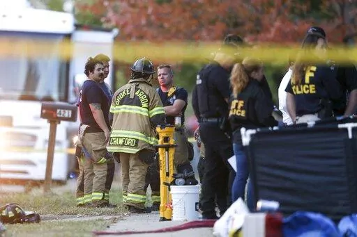 Police and firefighters investigate the scene of a house fire with multiple fatalities in Broken Arrow, Okla., outside Tulsa, Thursday, Oct. 27, 2022. Eight people were found dead after the fire was extinguished and police said they were investigating the deaths as homicides. (Ian Maule/Tulsa World via AP)