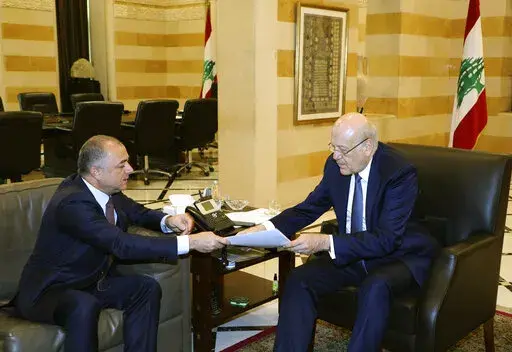 In this photo released by Lebanon's official government photographer Dalati Nohra, Lebanese Prime Minister Najib Makati, right, receives the final draft of the maritime border agreement between Lebanon and Israel from his deputy Elias Bou Saab who leads the Lebanese negotiating team, in Beirut, Lebanon, Tuesday, Oct. 11, 2022. Israel's prime minister said Tuesday that the country has reached an "historic agreement" with neighboring Lebanon over their shared maritime border after months of U.S.-b