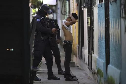A police officer searches and checks the documents of a man living in the Kiwanis Community, during a preventive patrol in search of gang members in Soyapango, El Salvador, Tuesday, Aug. 16, 2022. A May 2023 report by the human rights organization Cristosal, tallied 153 incarceration deaths during the first year of the state of emergency in El Salvador. No victim had been convicted of the alleged crime that put them behind bars. (AP Photo/Salvador Melendez, File)
