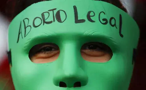 An abortion-rights activist wears a mask with text that reads in Spanish "Legal Abortion" during a rally outside Congress as lawmakers debate a bill that would legalize abortion, in Buenos Aires, Argentina, Tuesday, Dec. 29, 2020. In Argentina, lawmakers in late 2020, passed a bill legalizing abortion until the 14th week. (AP Photo/Natacha Pisarenko, File)