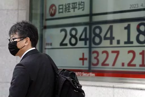 A person walks past in front of an electronic stock board showing Japan's Nikkei 225 index at a securities firm Friday, April 14, 2023, in Tokyo. Asian stock markets followed Wall Street higher on Friday after U.S. inflation eased in March and China reported unexpectedly strong exports. (AP Photo/Eugene Hoshiko)