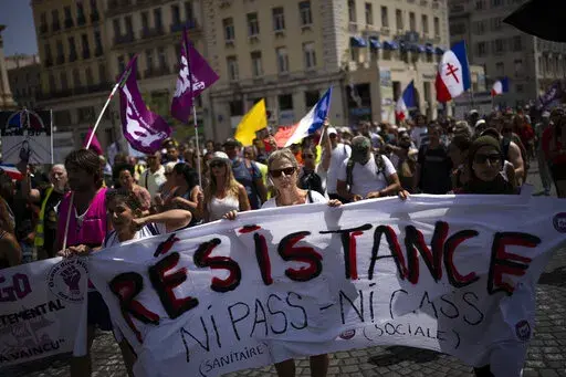 Protesters march during a demonstration to denounce a COVID-19 health pass needed to access restaurant, long-distance trains and other venues. in Marseille, southern France, Saturday, Aug. 14, 2021. The run-up to the April election comes in a context of mounting violence targeting elected officials in France, with holders of public officers targeted for their politics and by opponents of COVID-19 vaccinations restrictions. (AP Photo/Daniel Cole, File)