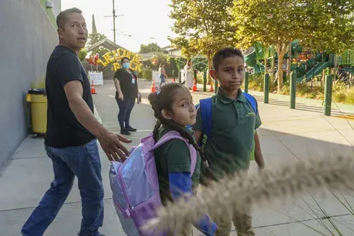 Roberto Garcia drops his children, Lily, 7, center, and Jack, 9, off for their first day of school in East Los Angeles on Wednesday, Aug. 14, 2024. (AP Photo/Damian Dovarganes)