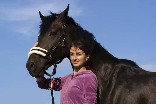 Viktoria Skliar poses for a photo Monday Aug. 8, 2022 with the horse 'Canada' at the stables called "Magnat" in the Kyiv region. In the last, brief conversations Skliar had with Oleksii Kisilishin, her detained boyfriend, the Ukrainian prisoner of war was making tentative plans for life after his release in an upcoming exchange with Russia. The next time Skliar saw Kisilishin, he was dead — one of several bodies in a photo of people local authorities said were killed when blasts ripped through
