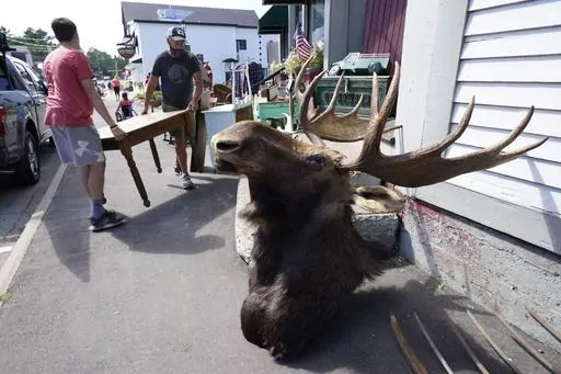 Two men carry a table into Camp Camp Moosehead Lake Indian Store, a gift shop and vintage store, Saturday, Aug. 15, 2020 in York Beach, Maine. Maximalism is a design trend emphasizing more color, texture and one-of-a-kind pieces. However, filling your home with ample layers of eye-catching decor can feel intimidating and seem expensive. To avoid maxing out your budget, shop at vintage stores and estate sales for unique finds. (AP Photo/Robert F. Bukaty, File)