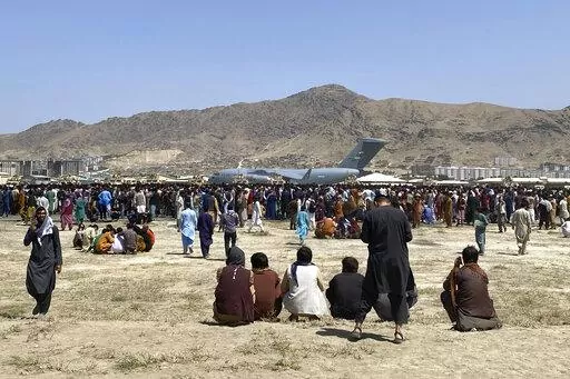 Hundreds of people gather near a U.S. Air Force C-17 transport plane at the perimeter of the international airport in Kabul, Afghanistan, Aug. 16, 2021. An Afghan couple who arrived in the U.S. as refugees are suing a U.S. Marine and his wife for allegedly abducting their baby. (AP Photo/Shekib Rahmani, File)