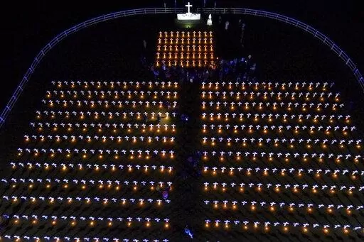 Candles illuminate crosses on a field during an event to remember the Argentinean soldiers who died during the Falklands or Malvinas War, marking the 40th anniversary of the war between Argentina and Great Britain over the remote South Atlantic archipelago in Pilar, Argentina, Saturday, April 2, 2022. (AP Photo/Natacha Pisarenko)