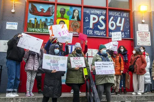 FILE — Teachers from the Earth School speak out on issues related to lack of coronavirus testing outside P.S. 64, Dec. 21, 2021, in New York. In the nation's largest school system, New York City, 2 million at-home test kits provided by the state will be used to increase testing following the break, the mayor announced this week. (AP Photo/Brittainy Newman, File)