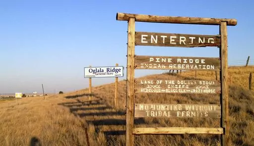 A sign hands outside the entrance to the Pine Ridge Indian Reservation in South Dakota, home to the Oglala Sioux tribe, Sept. 9, 2012. A tribe has banned Republican Gov. Kristi Noem from the Pine Ridge Reservation after she spoke this week about wanting to send razor wire and security personnel to Texas to help deter immigration at the U.S.-Mexico border and also said cartels are infiltrating the state's reservations. (AP Photo/Kristi Eaton, File)