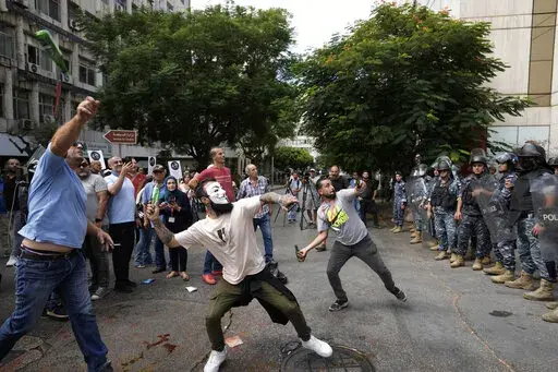 Protesters throw bottles glasses at the Lebanese Central Bank building, background, where the anti-government demonstrators rally against the Lebanese Central Bank Governor Riad Salameh and the deepening financial crisis, in Beirut, Lebanon, Wednesday, Oct. 5, 2022. Lebanon's once burgeoning banking sector has been hard hit by the country's historic economic meltdown, suffering staggering losses worth tens of billions of dollars and leaving the future of the small nation's lenders unknown betwee