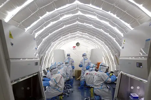In this file photo released by China's Xinhua News Agency, staff members work in an inflatable COVID-19 testing lab provided by Chinese biotech company BGI Genomics, a subsidiary of BGI Group, in Beijing, June 23, 2020. (Chen Zhonghao/Xinhua via AP, File)