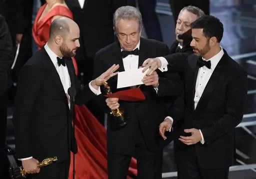 "La La Land" producer Jordan Horowitz, left, presenter Warren Beatty, center, and host Jimmy Kimmel right, look at an envelope announcing "Moonlight" as best picture at the Oscars on Sunday, Feb. 26, 2017, in Los Angeles. It was originally announced mistakenly that "La La Land" was the winner. (Photo by Chris Pizzello/Invision/AP, File)