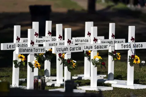 Crosses with the names of Tuesday's shooting victims are placed outside Robb Elementary School in Uvalde, Texas, Thursday, May 26, 2022. The 18-year-old man who slaughtered 19 children and two teachers in Texas left a digital trail that hinted at what was to come.  (AP Photo/Jae C. Hong)