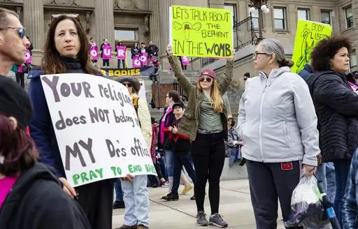 Boise, Idaho, resident Autumn Myers holds a sign with the Republican Party elephant symbol inside the outline of a uterus that reads, "Let's talk about the elephant in the womb," during a Planned Parenthood rally for abortion rights at the Idaho Statehouse in downtown Boise, May 14, 2022. Idaho lawmakers are considering a measure that would bar adults from taking minors to obtain an abortion without their parent's consent. (Sarah A. Miller/Idaho Statesman via AP, File)